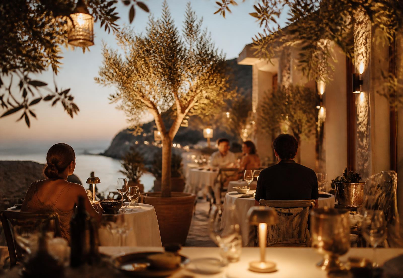 Guests dining on a candlelit Mediterranean terrace at dusk